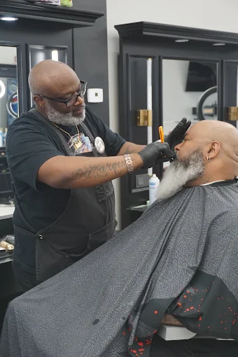 Barber working a fade beneath a warm ring light